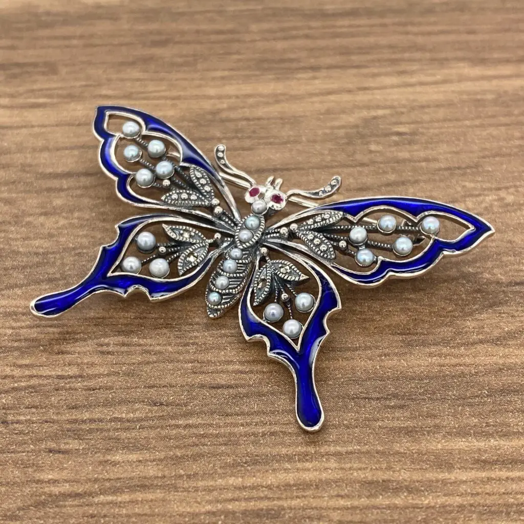 A butterfly brooch with pearls and blue enamel.