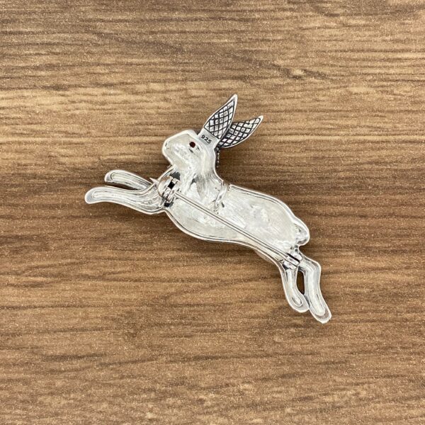 Silver rabbit brooch with red stone.