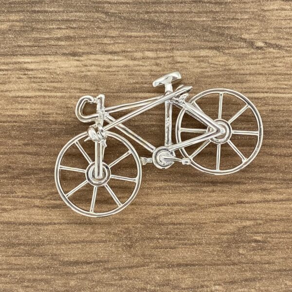 Silver bicycle charm on wood background.