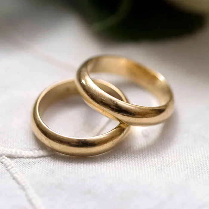 Two gold wedding rings on a white cloth.