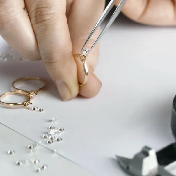A person is working on a ring with a pair of pliers.