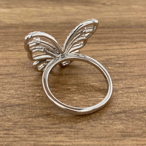 Silver butterfly ring on wood background.