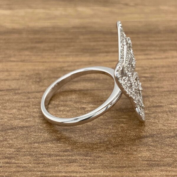 Diamond butterfly ring on a wooden surface.