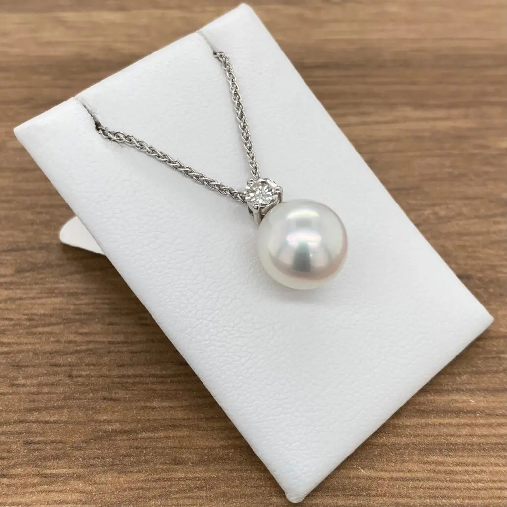 A white pearl and diamond necklace on a white background.