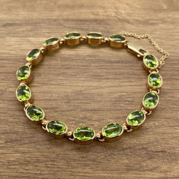 An oval peridot bracelet on a wooden table.