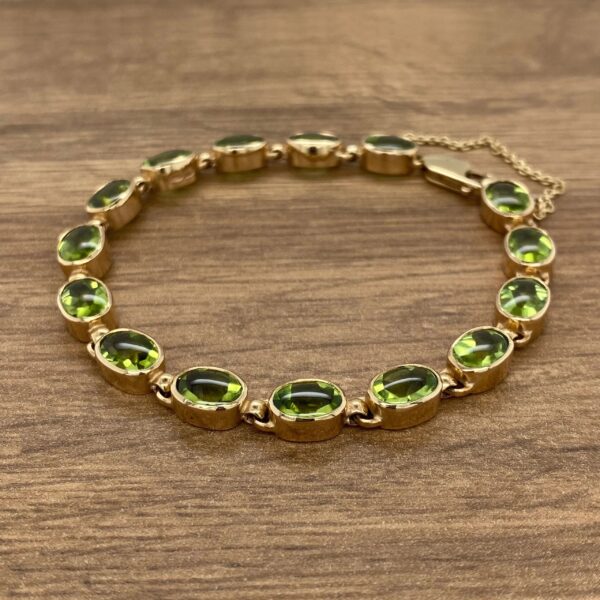 Gold bracelet with green oval gems.