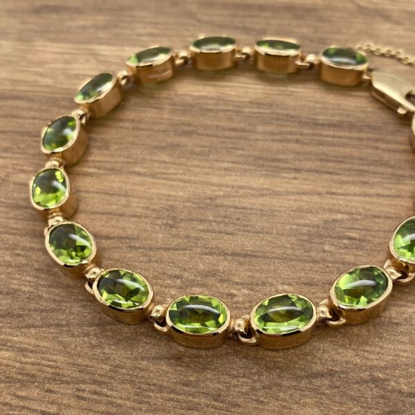 Gold bracelet with green oval gemstones.