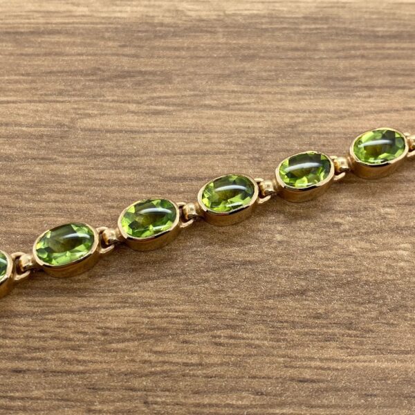 Gold bracelet with green oval stones.