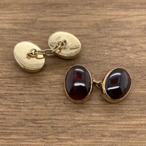 A pair of gold cufflinks with red and black stones.