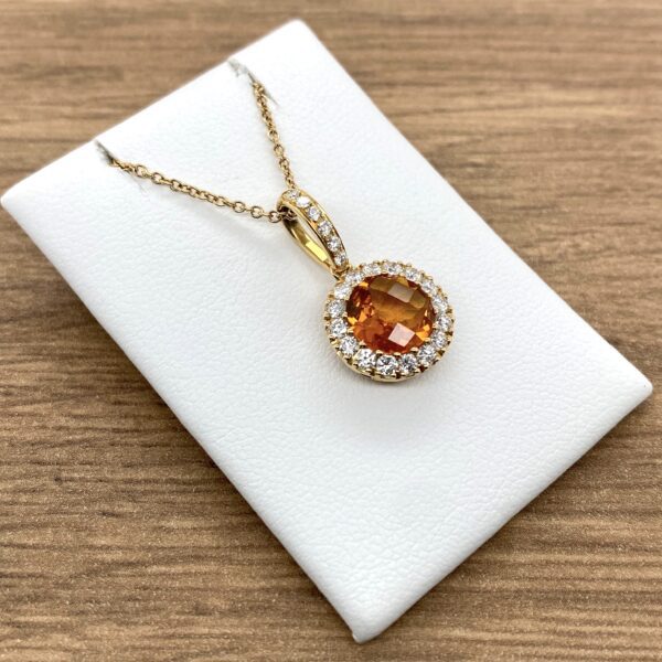 Gold necklace with orange gemstone pendant.