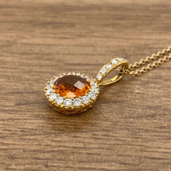 Gold pendant with orange gemstone and diamonds.