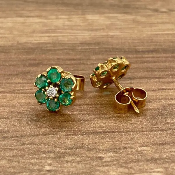 Gold earrings with emerald and diamond flower design.