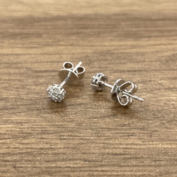 Diamond stud earrings on wood background.