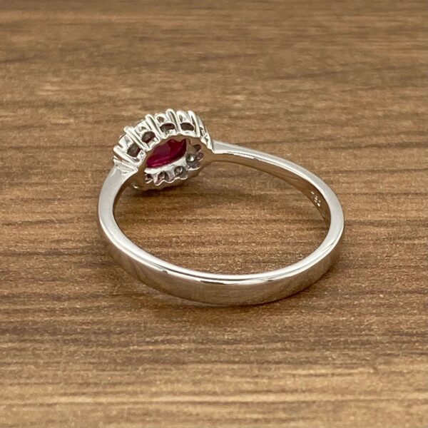 Silver ring with red gemstone and diamonds.