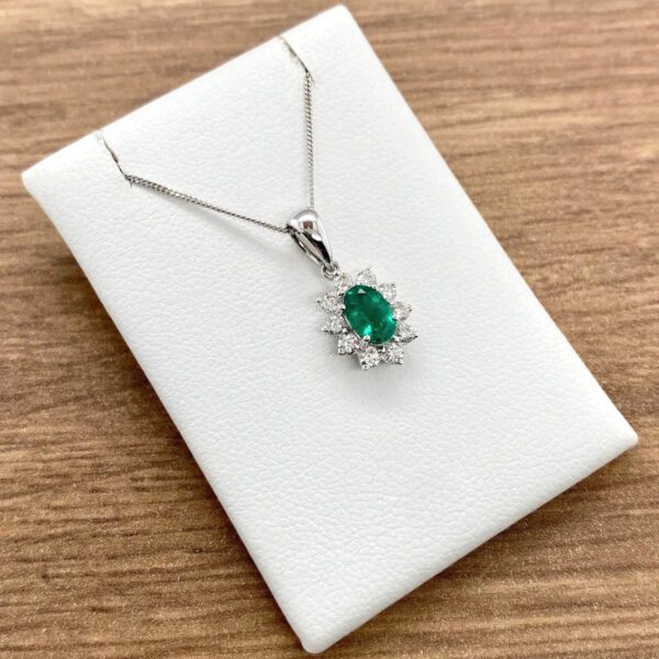 Emerald and diamond pendant necklace on display.