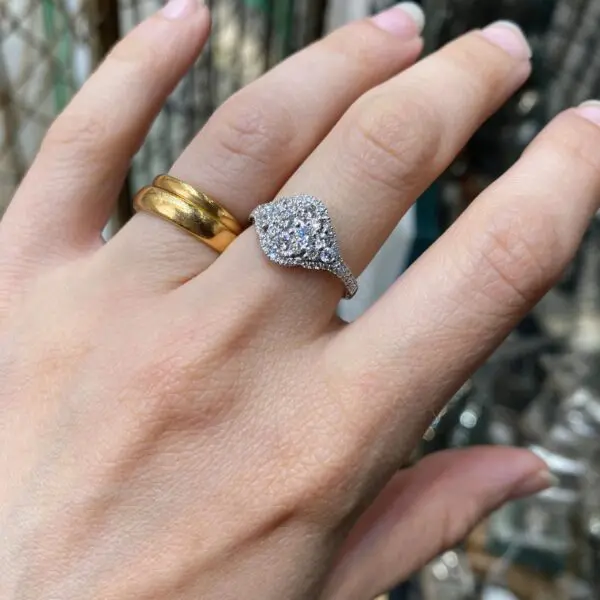 Hand wearing a diamond ring and a gold band.