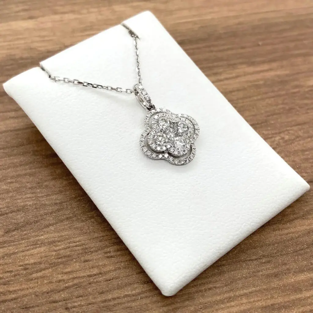 Diamond clover pendant necklace on white pad.