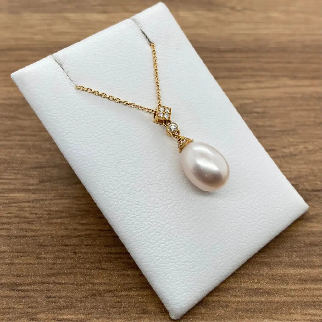 Gold necklace with pearl and diamond pendant.