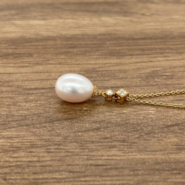 Pearl and diamond pendant necklace on wood.