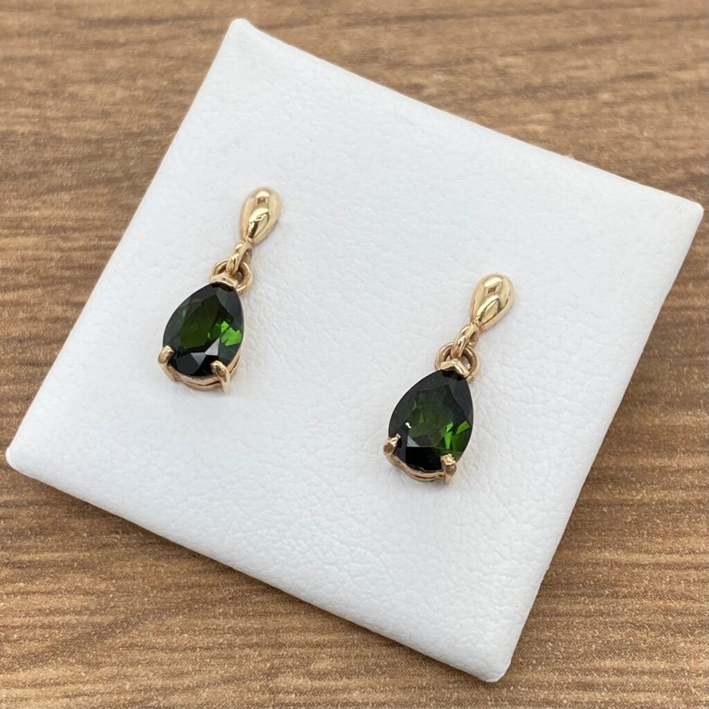 Gold earrings with green pear-shaped stones.