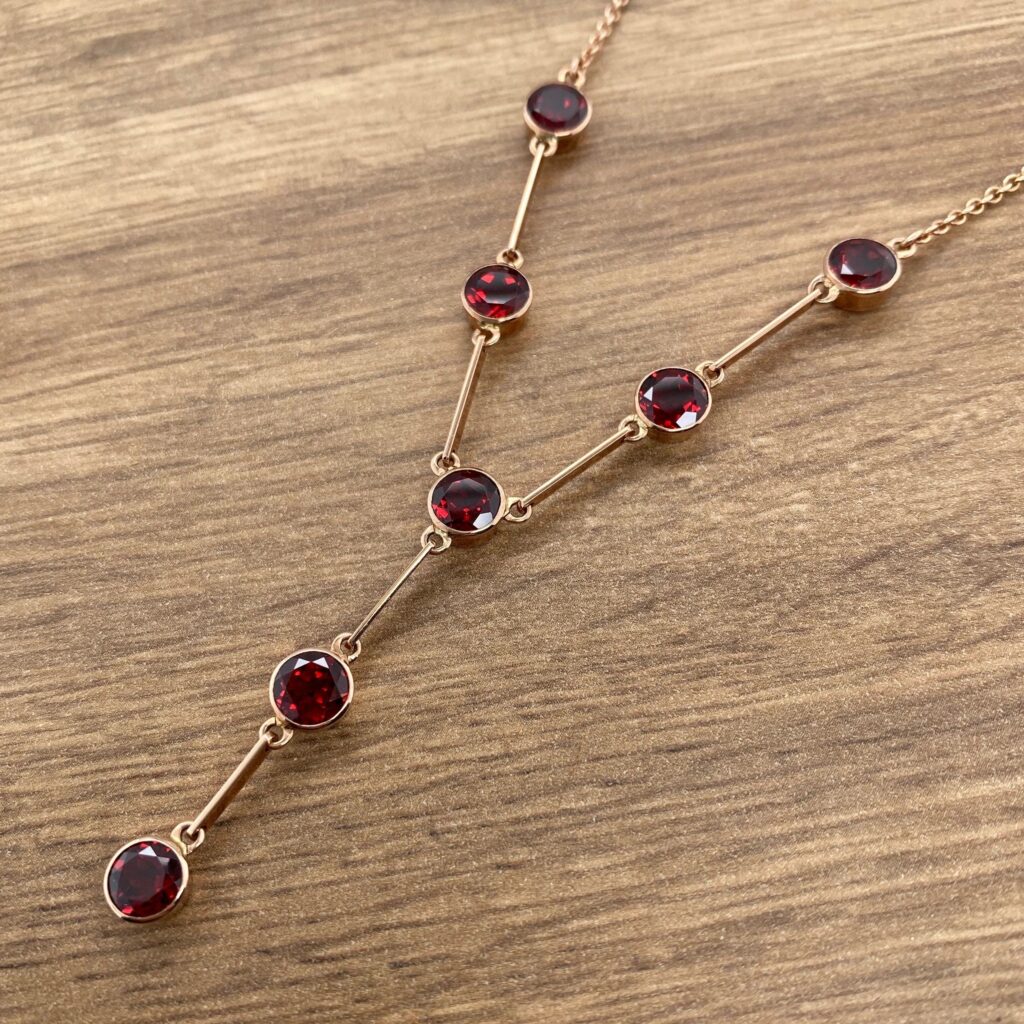 Gold necklace with red gemstone accents.