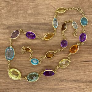 A multi colored gemstone necklace on a wooden table.
