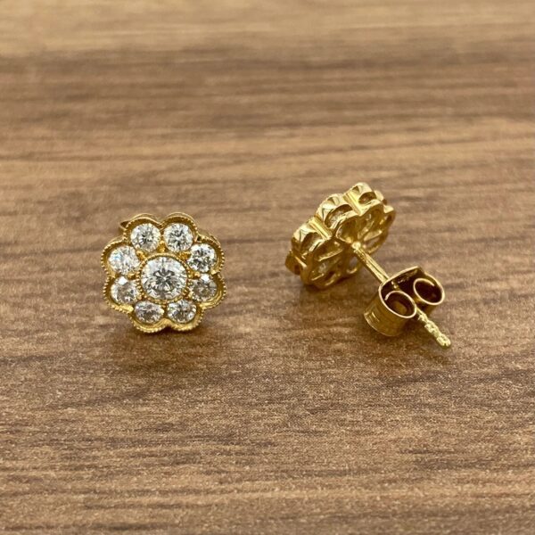 Gold diamond flower earrings on wood.