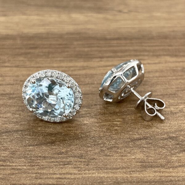 Pair of oval aquamarine earrings with diamond halo.