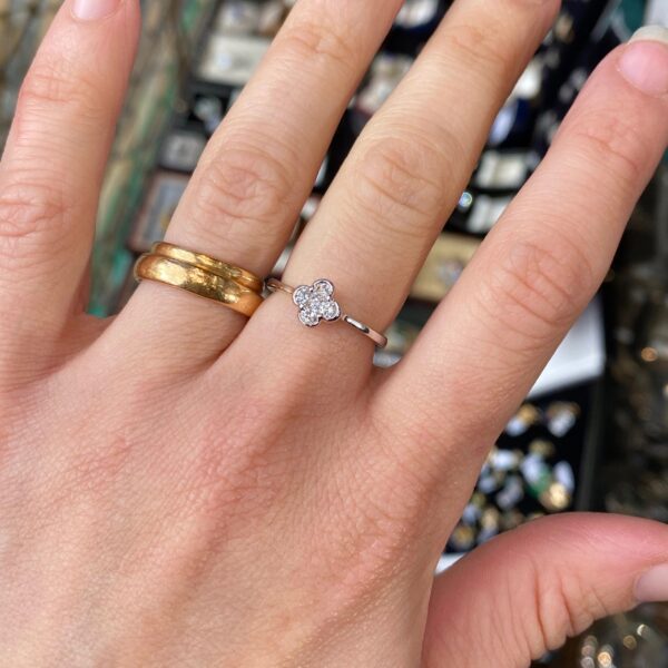 Hand wearing a diamond flower ring.