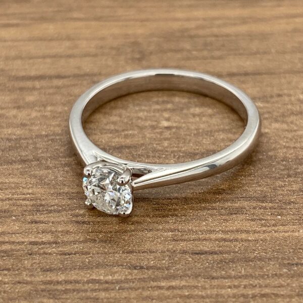 Solitaire diamond engagement ring on wood.