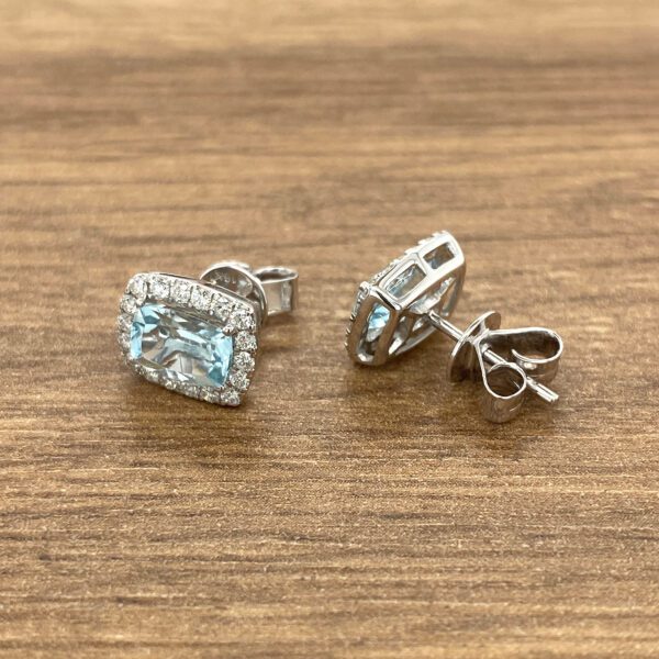 Diamond and aquamarine earrings on wood.