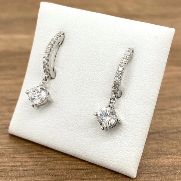 Diamond hoop earrings with dangling stones.