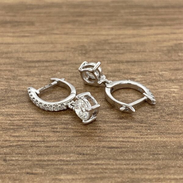 Diamond dangle earrings on wooden surface.