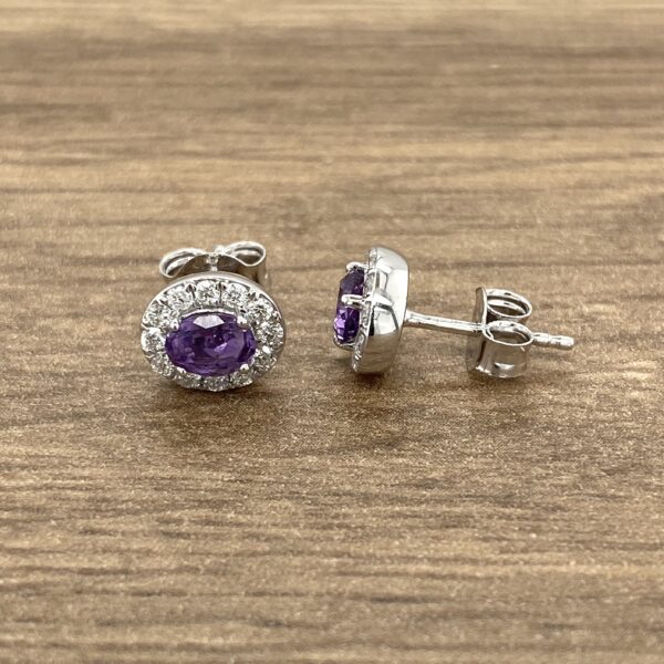 Silver earrings with purple gemstone halo.