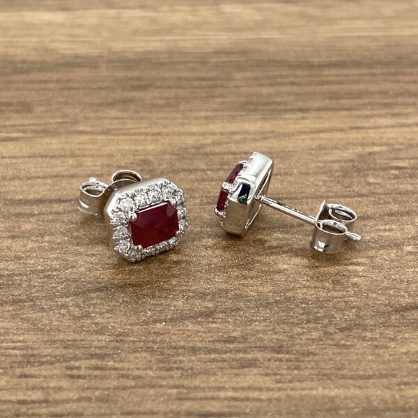 Ruby and diamond earrings on wood background.