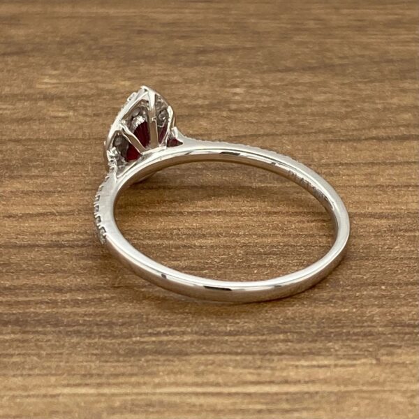 Silver ring with red gemstone and diamonds.