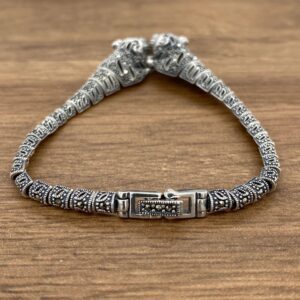 A silver bracelet with two tigers on it.