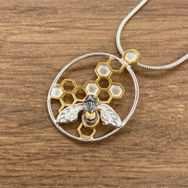 Silver and gold bee pendant with honeycomb.