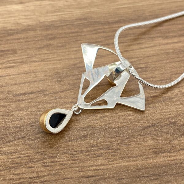 Silver necklace with black teardrop pendant.