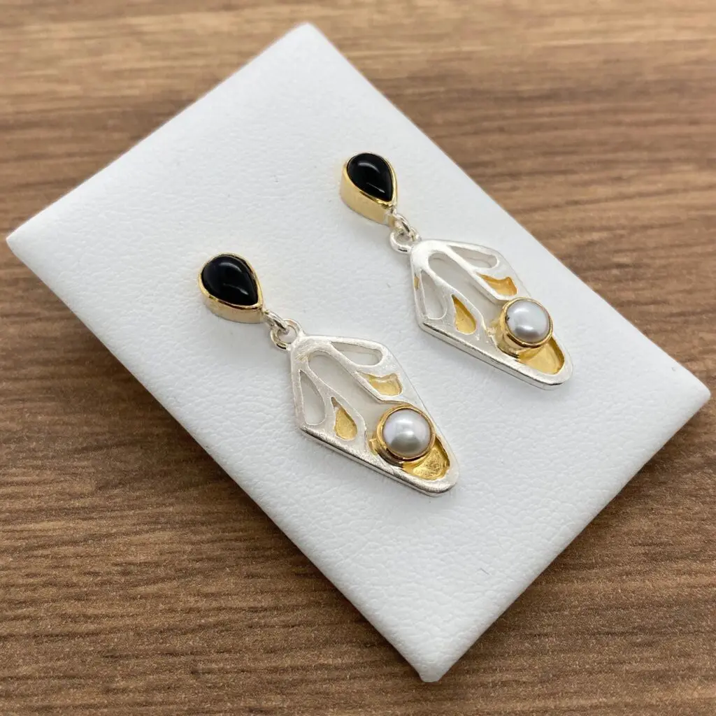 Silver and gold earrings with black and pearl stones.