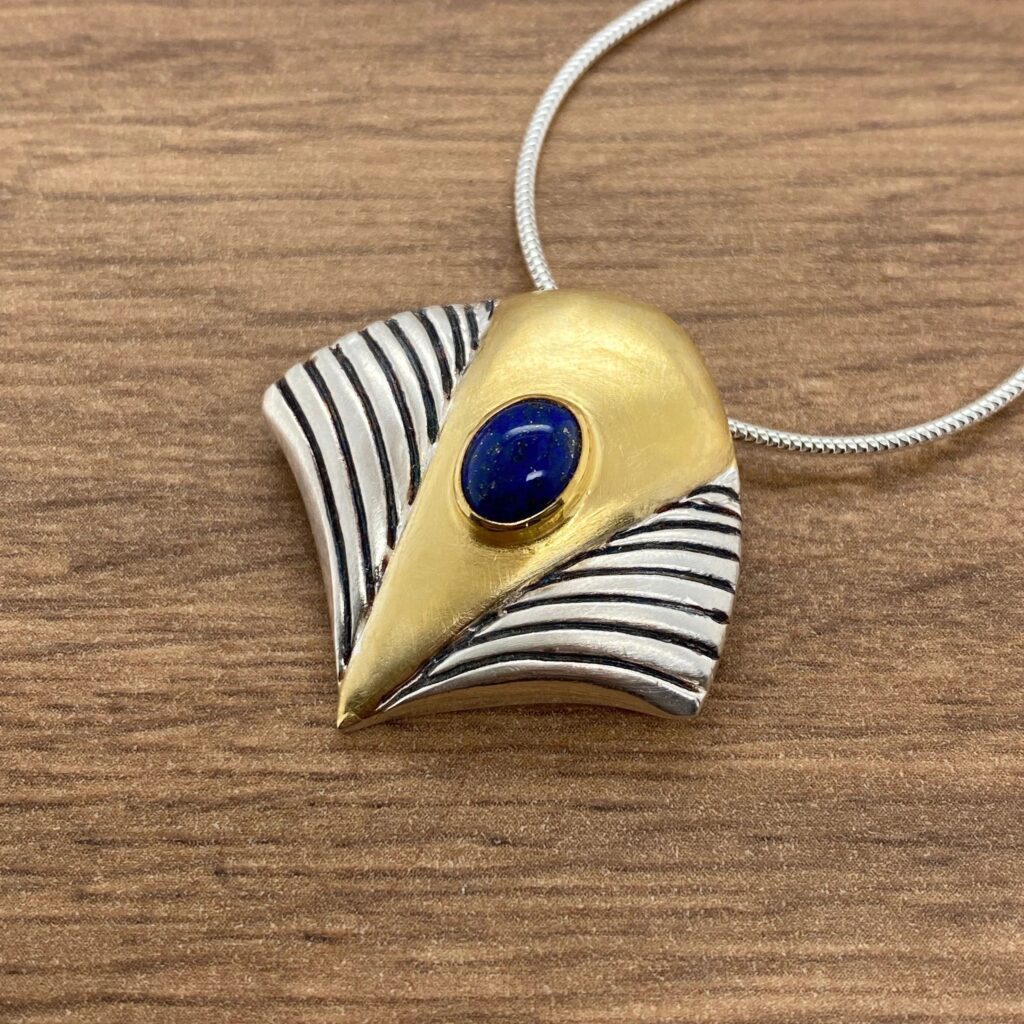 Gold and silver pendant with a blue stone.