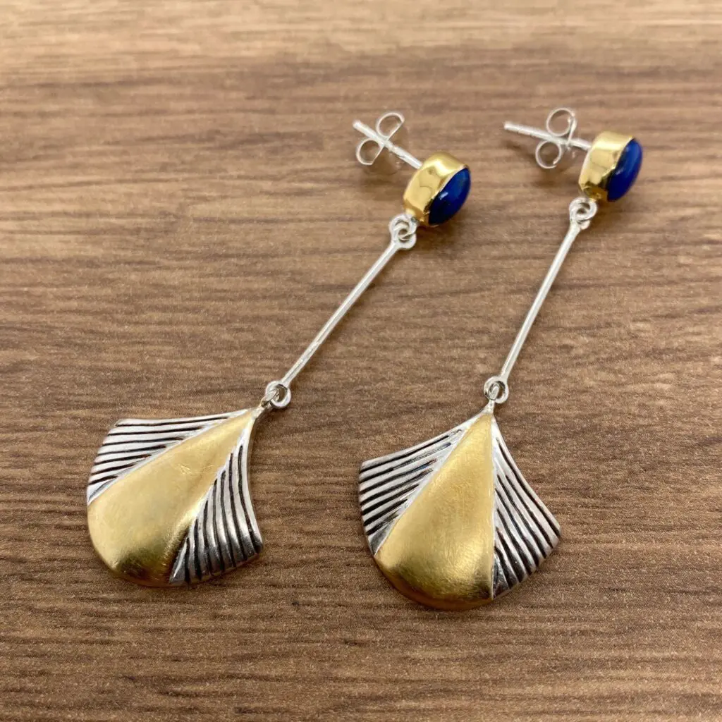 Silver and gold geometric earrings with blue stones.