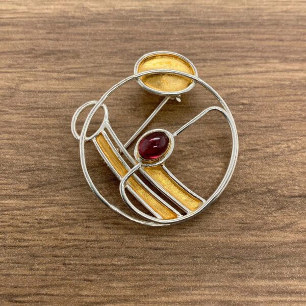 Silver and gold brooch with red gem