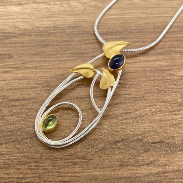 Silver and gold necklace with green and purple stones.