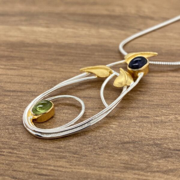 Silver and gold pendant with green and blue stones.