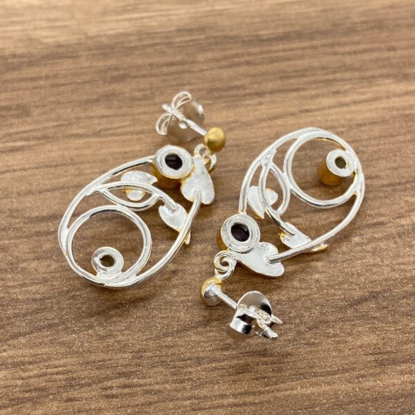 Silver and gold earrings with gemstone accents.