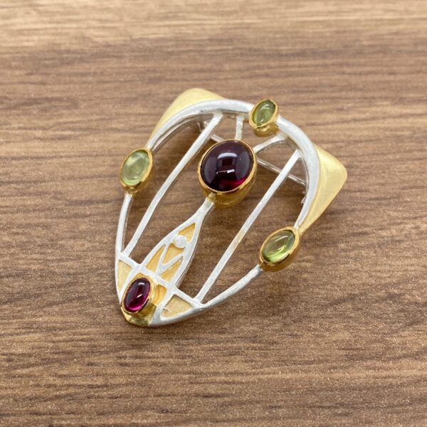 Silver and gold brooch with gemstones.