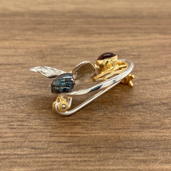 Gold and silver bee brooch with a gemstone.