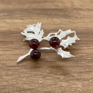 Silver holly sprig brooch with red berries.