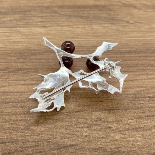 Silver holly leaf brooch with red berries.